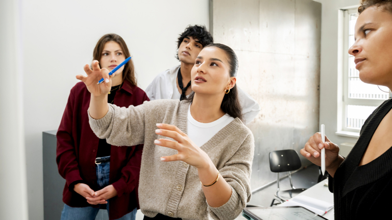 Een studente legt iets uit aan drie andere studenten