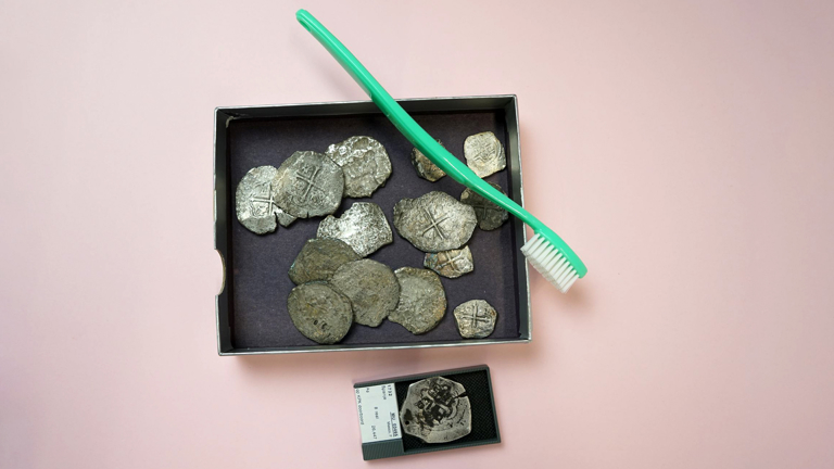 Tandenborstel ligt op een doos met historische muntstukken.