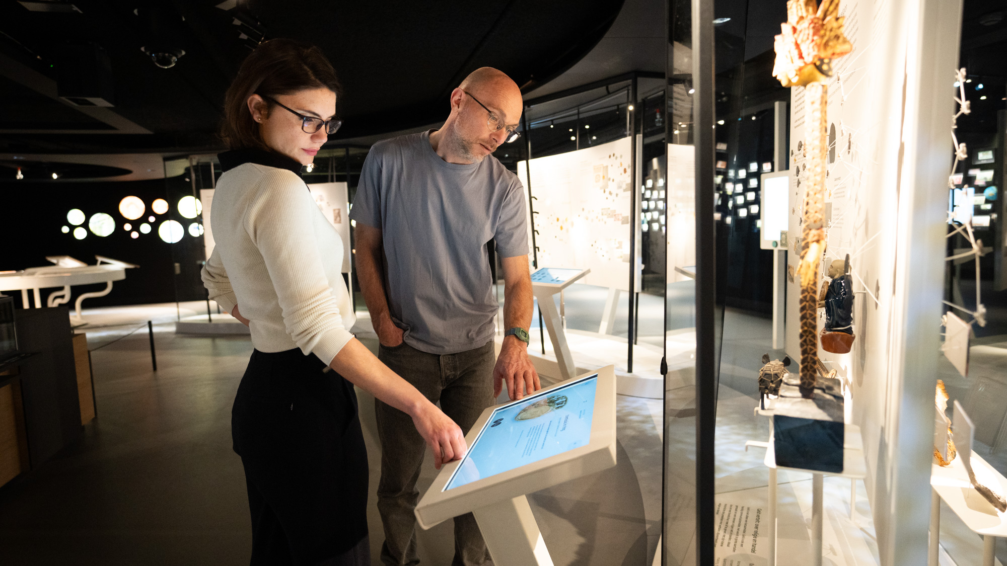 Mensen kijken naar objecten uit de numismatische collectie van DNB.