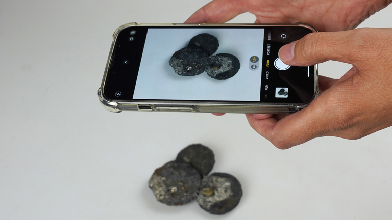 Historische munten worden gefotografeerd met een telefoon.