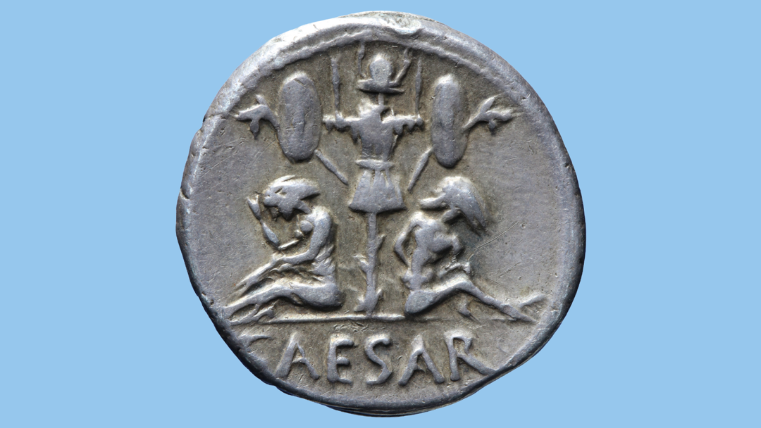 Keerzijde van een zilveren munt van Caesar met een trofee bestaande uit buitgemaakte Keltische wapens en twee Kelten: links een treurende vrouw en rechts een man met de handen op zijn rug gebonden.